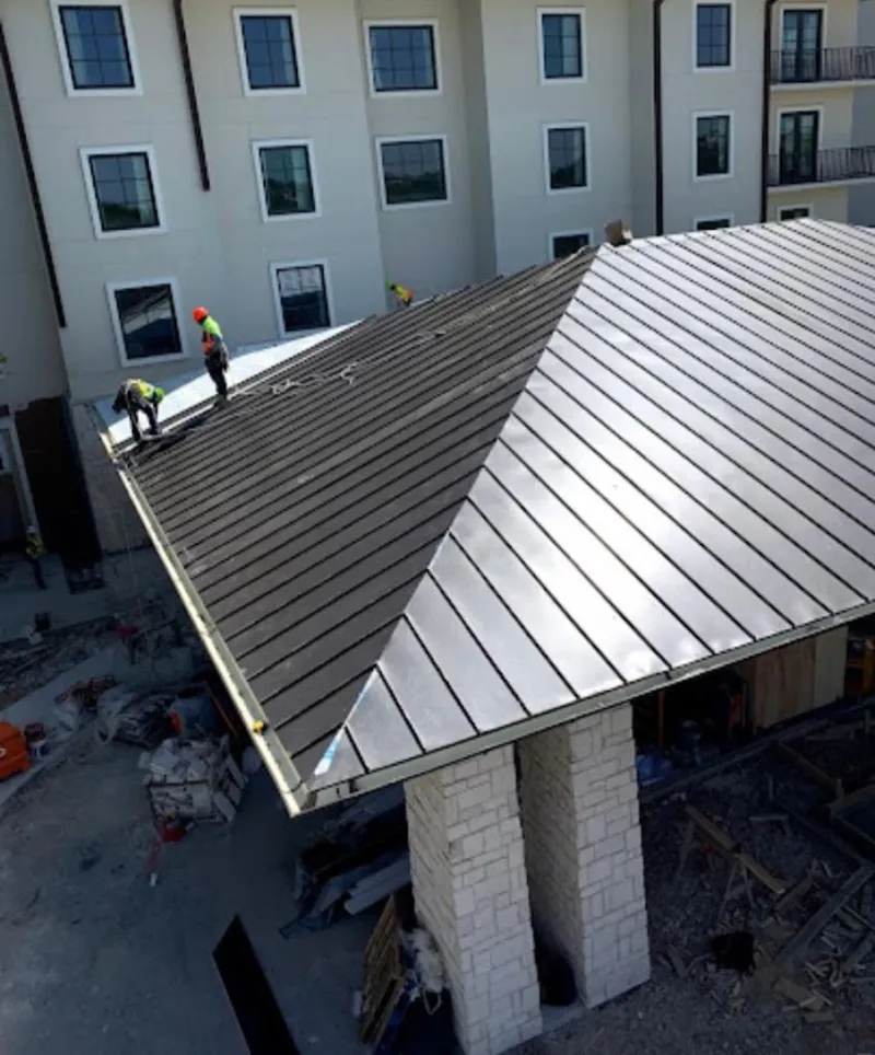 Crew installing standing seam metal roof panels on a commercial project in Williams